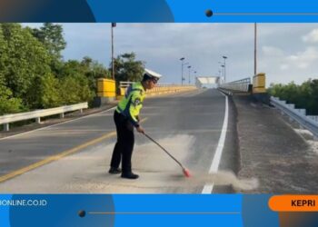 Ganggu Kamseltibcarlantas, Personil Satlantas Bersihkan Tumpahan Pasir di Jalan Lintas Barat