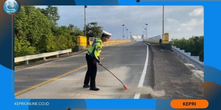 Ganggu Kamseltibcarlantas, Personil Satlantas Bersihkan Tumpahan Pasir di Jalan Lintas Barat